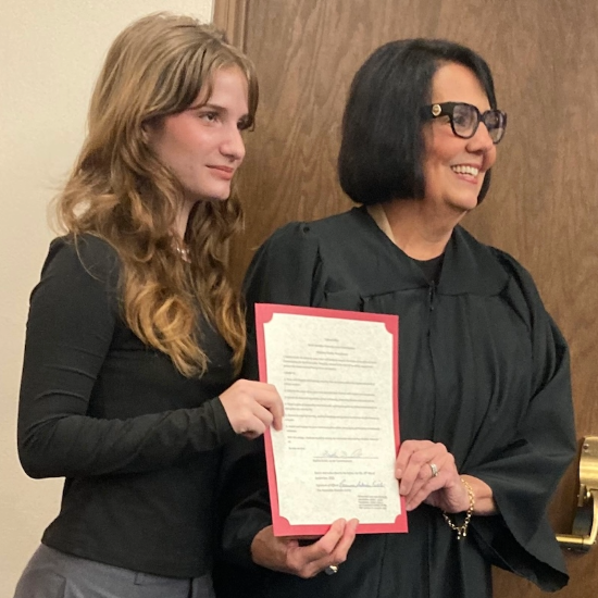 Sophia and judge hold document at her swearing in ceremony